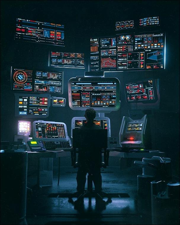 A programmer at the desk with a lot of monitors in front of him. 